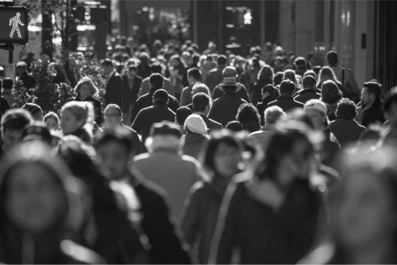 Crowd of people walking on a city street in black and white.