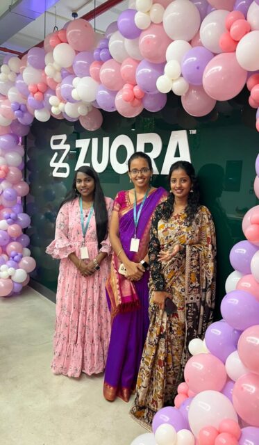 Three women standing in front of balloons with the word zura.