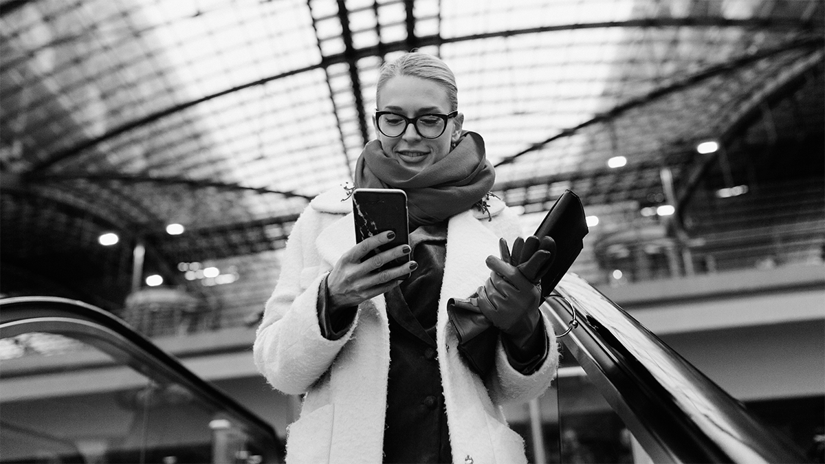 Woman on an escalator looking at her smartphone.