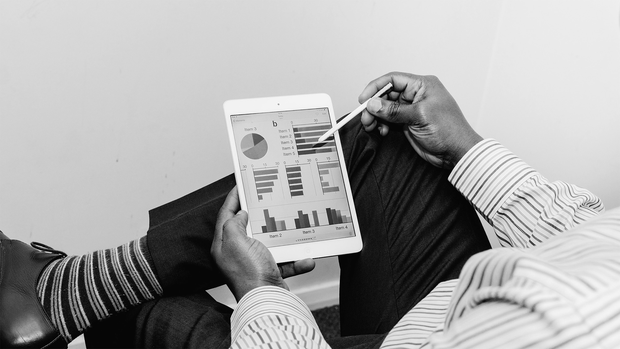 A person seated while analyzing graphs on a digital tablet.