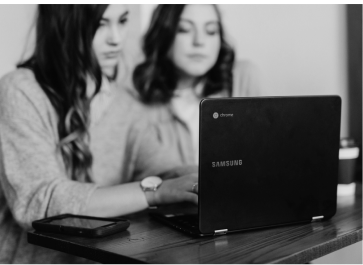 Two individuals collaborating at a table with a samsung laptop and a tablet.