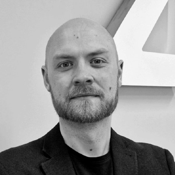 Black and white photo of a bald man with a beard, dressed in a suit jacket, smiling slightly and looking directly at the camera at Zuora Subscribed Live.