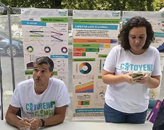 Two people at a booth with informational posters behind them.