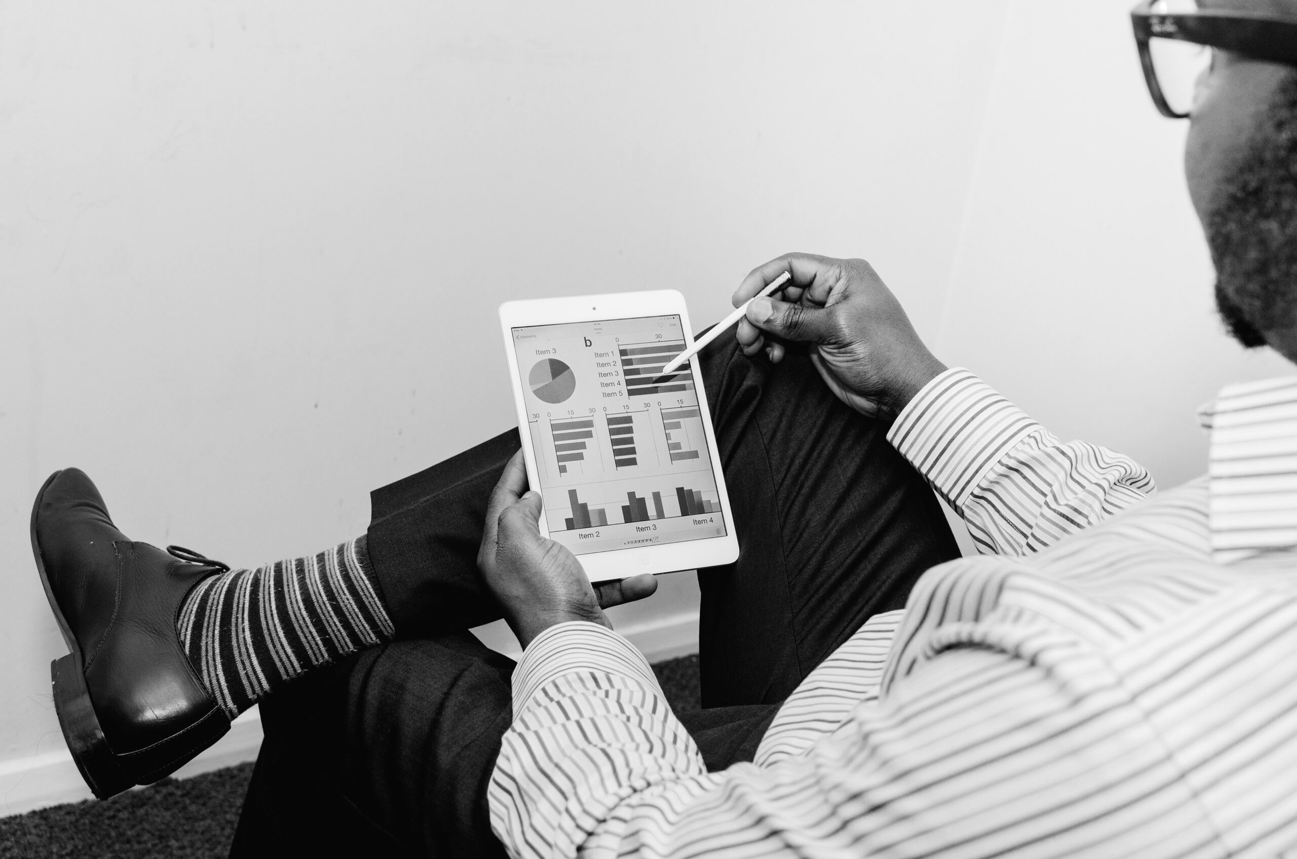A person in business attire uses a stylus on a tablet displaying charts and graphs, analyzing the latest CFO trends.