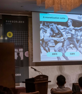 ある会議で、レースに出場するランナーを映したプレゼンテーションのスライドが表示された。画像の上のスライドに「A monetization suite」というテキストが見える。.